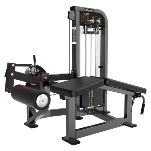 Aerofit prone leg curl machine with selectorized weight stack, padded lying bench, adjustable ankle roller, and heavy-duty frame for commercial gym hamstring training.